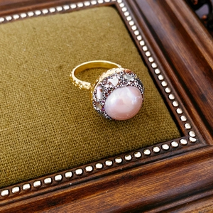 Macro detail of vintage gold plated ring with large pearl and micro-inlaid rhinestones