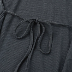 Macro view of charcoal grey ribbed knit fabric and tie detail on a long sleeve top