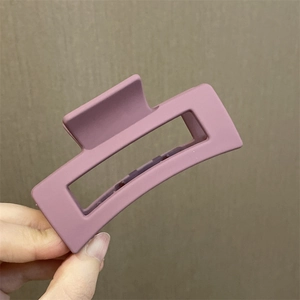 Primer plano detallado de una pinza para el cabello rectangular rosa mate de plástico