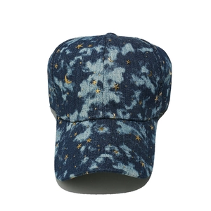 Close-up of dark blue denim baseball cap featuring golden star and moon pattern