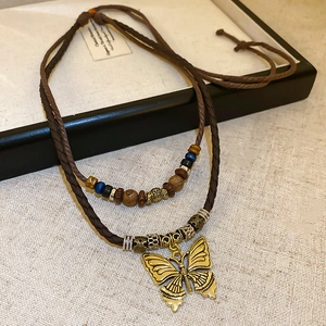 Detail of double-layer woven necklace featuring vintage gold butterfly pendant and beads