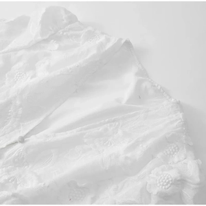Détails de broderie en dentelle blanche et textures ajourées sur la robe en gros plan