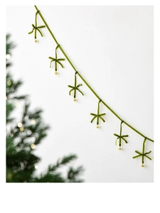 Detail of green velvet Christmas banner with small golden bells and handmade bows