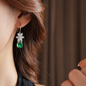Détail de boucles d'oreilles fleur en argent avec pendentif goutte d'émeraude verte