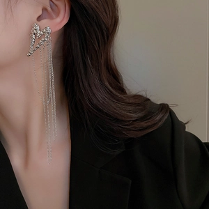 Close-up of heart-shaped lava fringe earrings worn by a model in a black blazer