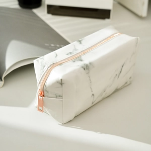 Macro detail of white marble pattern pencil case with elegant rose gold zipper