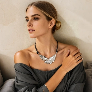Vue détaillée du pendentif plume argenté avec texture sur un cordon noir pour femmes