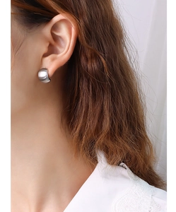 Detail of silver C-shaped titanium steel earring with a brushed metallic finish