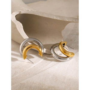 Macro detail of two-tone C-shaped earrings in polished gold and silver stainless steel
