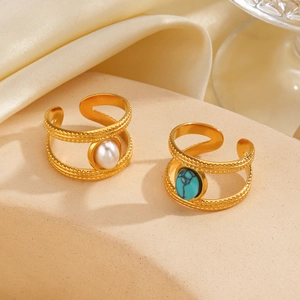 Gold stainless steel ring with faux pearl and turquoise on a beige textured stone base