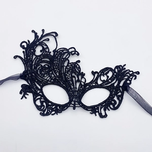 Detailed view of intricate black lace mask with elegant scrollwork and satin ties