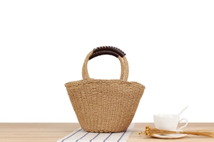 Detail of hand-woven straw tote with brown leather handles and striped fabric background