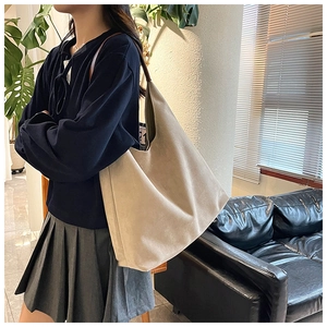 Side view of a large beige suede tote bag shown on model for a casual commute look