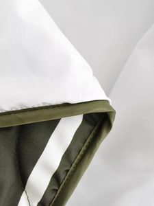 Détail de la couture en tissu matelassé blanc et vert foncé de cette veste d'hiver vintage