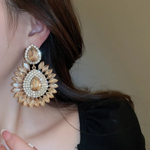 Macro shot of luxury teardrop floral earring with champagne rhinestones on model