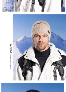 Close-up of beige ribbed knit beanie with mountain pattern and leather logo patch