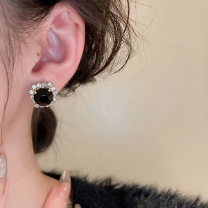 Gros plan d'une boucle d'oreille géométrique avec gemme noire et entourage de diamants