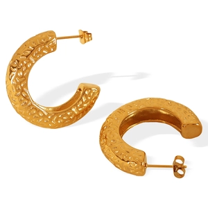 Gold C-shaped chunky hoop earrings with textured hammered finish on white background