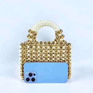 Close-up of golden and pearl beaded handbag shown with smartphone for size comparison