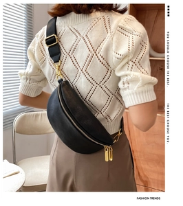 Detail of black lychee grain fanny pack with gold hardware worn by a model in a modern room