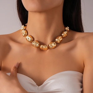 Close-up of chunky gold-toned irregular textured beads necklace on female neck