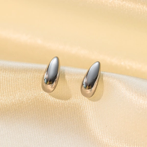 Sleek teardrop stainless steel stud earrings in polished silver on soft silk background