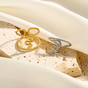 Detailed shot of gold and silver snake rings on a travertine stone with silk fabric