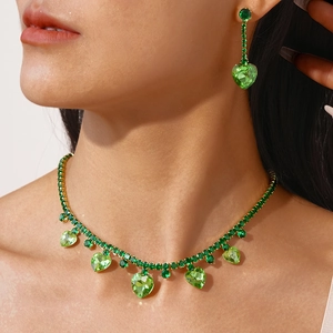 Detail of green heart zirconia necklace and tassel earrings set on a model's neck