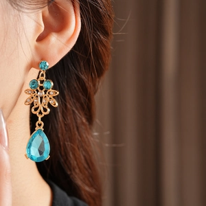 Macro view of gold vintage earrings with blue teardrop gemstones and palace style design