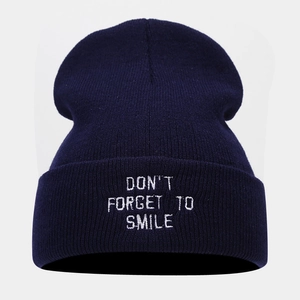 Detail of navy knit beanie featuring white embroidered Don't Forget To Smile text