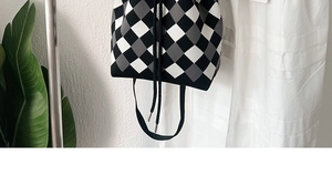 Detail of knit bucket bag with tricolor checkerboard pattern and drawstring closure