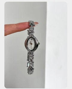 Detail of silver floral bracelet watch with diamond-encrusted camellia links and oval dial