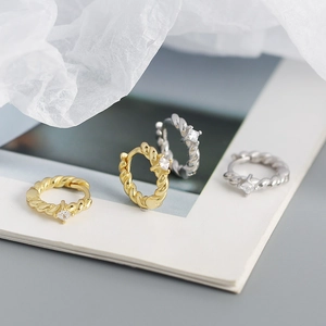 Detail of twisted cable hoop earrings in gold and silver with square zircon stones