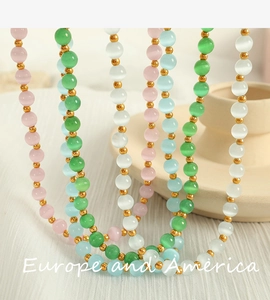 Close-up of pastel cat eye bead necklaces in pink and blue with gold accents