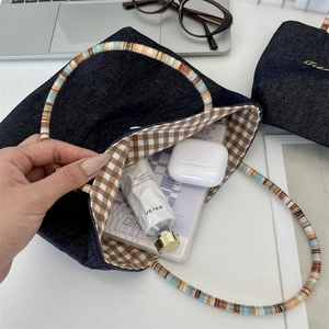 Detail of denim mini tote bag with checkered lining and colorful braided handle texture