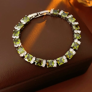 Primer plano detallado de pulsera de circonitas verde esmeralda sobre cuero oscuro