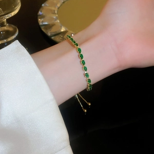 Close-up of adjustable gold chain bracelet with teardrop green zircon on a wrist