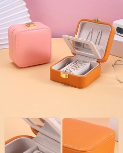 Detail of pink and orange jewelry box showing mirror, ring slots and leather texture