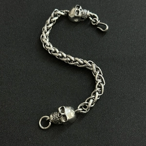 Detailed view of silver braided dragon bone bracelet with skull heads on black texture