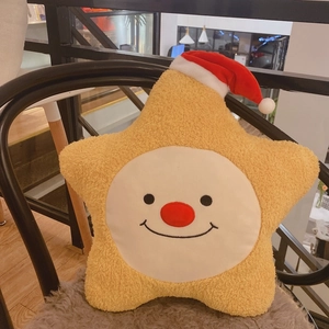 Detail eines weichen gelben Stern-Plüschkissens mit Smiley-Gesicht und festlicher Weihnachtsmütze