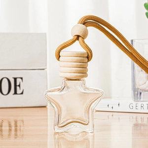 Star-shaped glass perfume pendant with wooden cap and yellow rope on wooden table