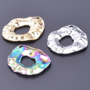 Detail of three irregular hammered metal circle pendants in gold, silver, and rainbow colors