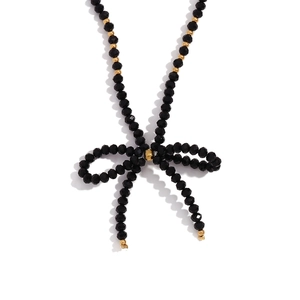 Collier classique avec perles noires facettées, détails dorés et pendentif noeud élégant