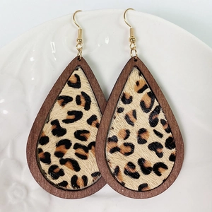 Detail of leopard print fur inlay in teardrop wood frame earrings on white plate