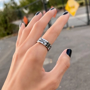 Close-up of titanium steel punk ring with black thorn pattern worn on finger
