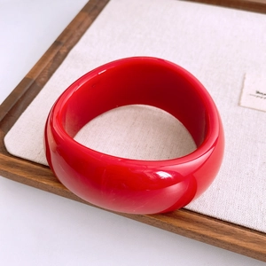 Gros plan détaillé d'un large bracelet en acrylique rouge vif avec une finition polie