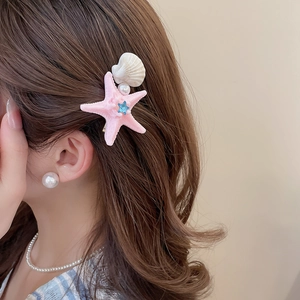 Close-up of starfish and shell hair clip with pearls on model for beach style