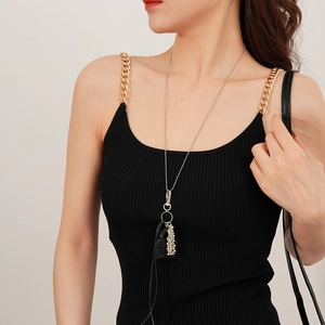 Détail d'un long collier argenté avec pendentif mini sac et gland en perles sur mannequin
