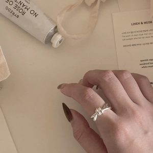 Detailed view of an S925 sterling silver knotted ring on a finger with aesthetic props