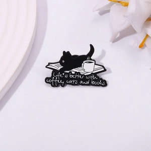 Detail of enamel pin featuring black cat, coffee, and books with Life is better text